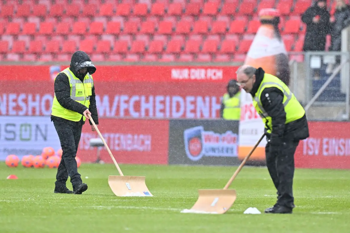 Ground staff work to clear snow ahead of a Bundesliga fixture affected by inclement weather this weekend.