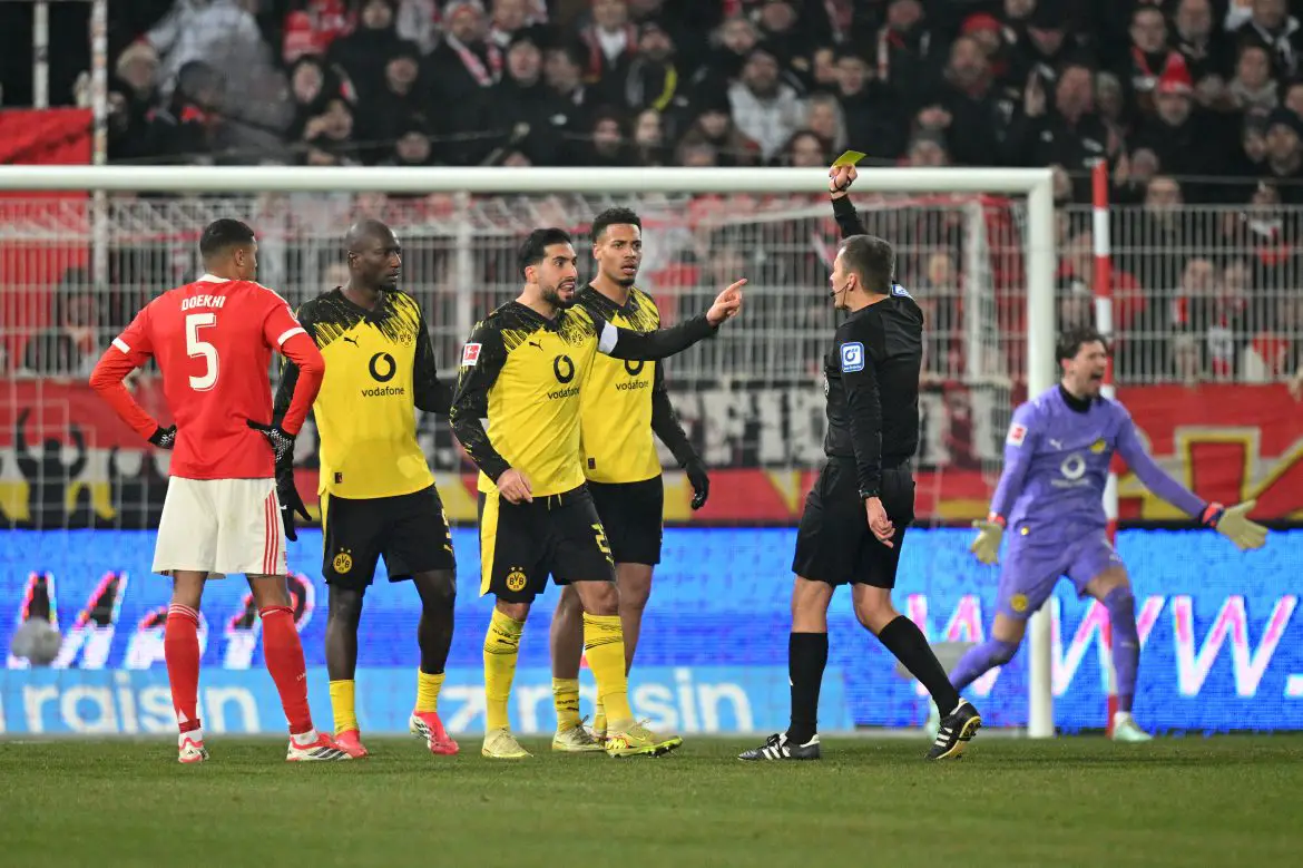 Bundesliga match official Robert Hartmann shows Borussia Dortmund's Emré Can a yellow card.