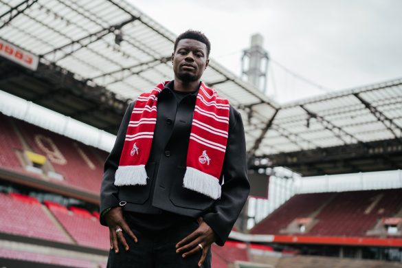 New 1. FC Köln signing Ragnar Ache at the club's stadium in a club scarf.