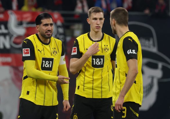Borussia Dortmund defenders Emré Can, Nico Shlotterbeck, and Waldemar Anton huddle up in a recent Bundesliga match.